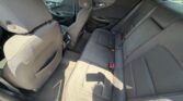 Rear interior of a car showing a dark fabric back seat (three seats) with headrests and red seat belt buckles.