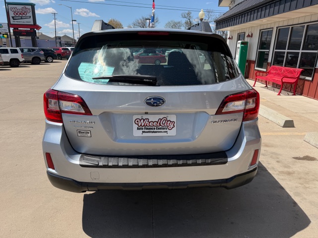 Silver Subaru Outback viewed from the rear in a dealership lot, with Wheel City license plate frame on the back.