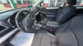 Interior of a Subaru sedan: steering wheel with logo, dashboard, gear shift, and front seats from the driver’s side perspective
