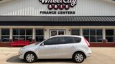 White compact hatchback parked in front of Wheel City Auto Finance Centers storefront.