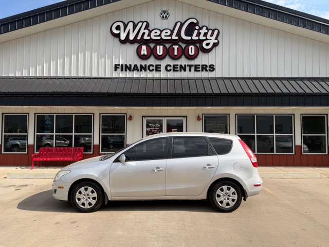 White compact hatchback parked in front of Wheel City Auto Finance Centers storefront.