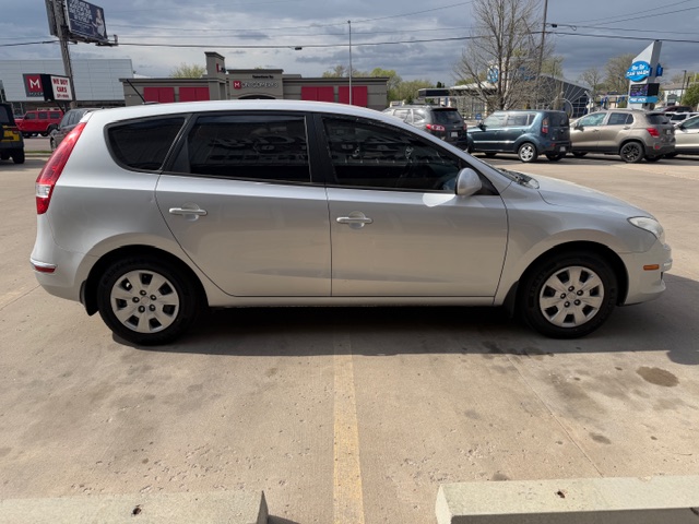 Side view of a silver compact hatchback parked in an outdoor parking lot.