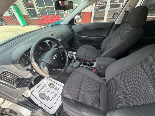 Interior of a Hyundai sedan: driver and front passenger seats, dashboard, steering wheel, and center console visible.