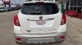 Rear view of a white Buick Encore in a dealership lot, showing the Wheel City Auto Finance license plate frame and red taillights.