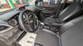 Black leather front seats and steering wheel of a car interior with a center console and dashboard, showing a gear shifter and floor mats.