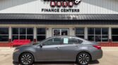Gray sedan parked in front of Wheel City Auto Finance Centers storefront with a red bench nearby (front of building).