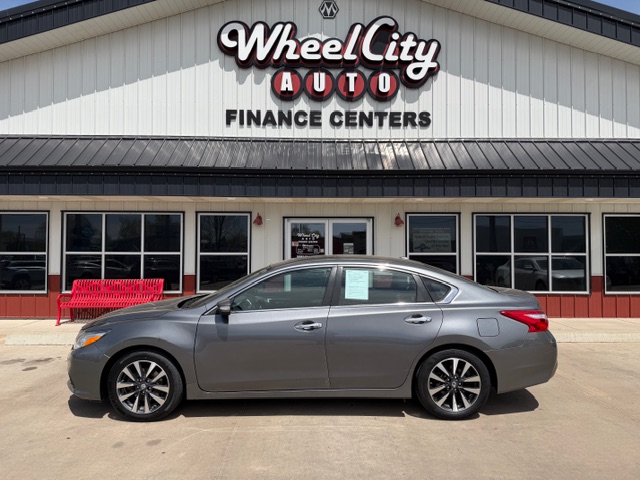 Gray sedan parked in front of Wheel City Auto Finance Centers storefront with a red bench nearby (front of building).