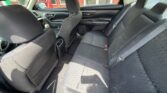Interior of a car showing the rear bench seat with three seating positions and seat belts, viewed from the driver's side door. Front seats are visible, and the cabin appears clean with dark upholstery.