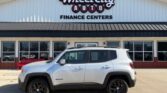 Silver Jeep Renegade SUV parked in front of Wheel City Auto Finance Centers storefront in a dealership lot.