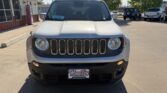 Front view of a white Jeep SUV in a car dealership lot, showing the seven-slot grille and round headlights; license plate reads Wheel City nearby.