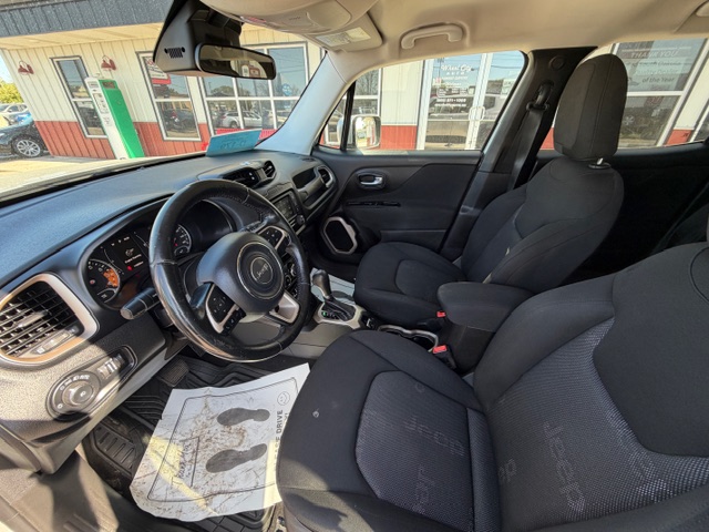 Dark gray SUV interior with the front seats, steering wheel, center console, and floor mat visible; driver’s side door open showing exterior scene outside the vehicle.