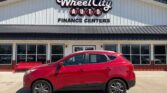 Red crossover SUV parked in front of Wheel City Auto Finance Centers storefront, a dealership building with large windows and a prominent sign.