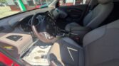 Interior of a red Hyundai from the driver’s side, showing the steering wheel, center console, and gray cloth front seats.