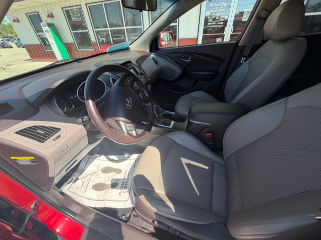 Interior of a red Hyundai from the driver’s side, showing the steering wheel, center console, and gray cloth front seats.