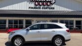 Silver SUV parked in front of Wheel City Auto Finance Centers dealership sign on a light-colored building.