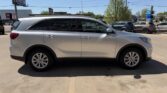 Side profile of a silver mid-size SUV parked in a sunny parking lot, with other cars in the background.