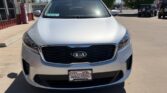 Front view of a white Kia SUV parked in a dealership lot, with a Wheel City Auto Finance Centers license plate frame.