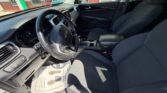 Driver's-seat interior of a black-cloth car with steering wheel, dashboard, and center console visible from the open door.