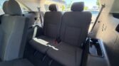 Car interior showing the back row with two black fabric seats, center belt buckles, and a built-in cup holder on the right panel