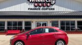 Red compact car parked in front of Wheel City Auto Finance Centers building, showroom windows visible behind.