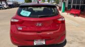 Rear view of a red Hyundai Elantra GT hatchback at a car dealership, with a sale tag in the rear window and a Wheel City Auto Finance plate frame.