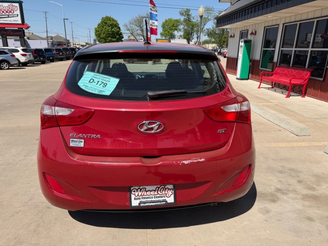 Rear view of a red Hyundai Elantra GT hatchback at a car dealership, with a sale tag in the rear window and a Wheel City Auto Finance plate frame.