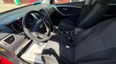Front interior of a black Hyundai sedan, showing the driver’s seat and steering wheel, center console, and front passenger seat as seen from the open driver's side door.