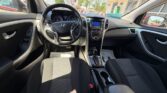 Interior view of a Hyundai from the driver's seat showing steering wheel, dashboard, and center console','Driver’s perspective of a car cabin with steering wheel, instrument cluster, and gear selector','Front seats and dashboard of a Hyundai, including steering wheel and infotainment display','Car interior: driver’s seat view with steering wheel, gear lever, and center console in a sunny showroom lot','Dashboard and steering wheel area of a compact sedan as seen from the front passenger seat