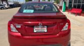 Rear view of a red Nissan Versa SV parked in a dealership lot; window sticker and Wheel City Auto Finance Centers plate frame are visible.
