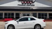 White sedan parked in front of Wheel City Auto Finance Centers dealership building.