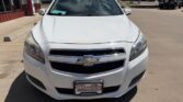 Front view of a white Chevrolet sedan parked in a dealership lot, license plate reads Wheel City Auto Finance Centers.