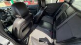 Interior of a black leather-sport sedan, front driver and passenger seats visible, rear bench seat in view from the open rear door.