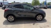 Side view of a dark gray compact SUV in a dealership lot, four doors, alloy wheels, and roof rails.