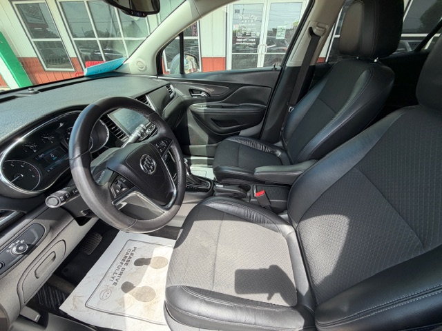 Driver's-side view of a modern car interior with black leather seats, steering wheel, and center console visible from the front passenger seat.