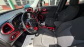 Driver's-seat view of a car interior with black seats and red trim accents, dashboard and steering wheel visible.