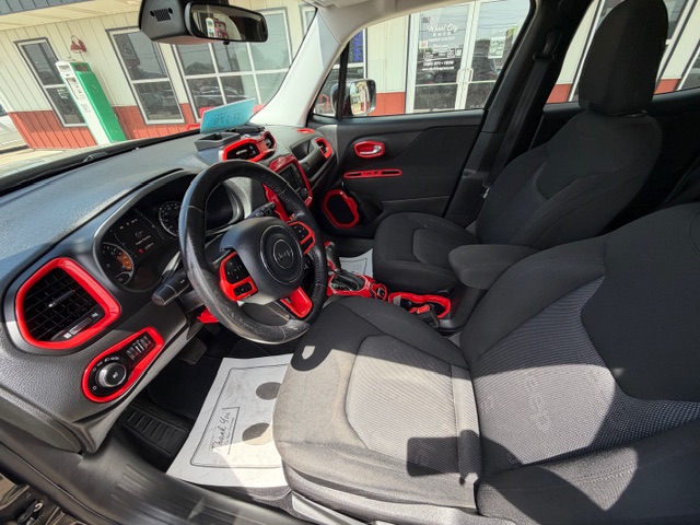 Driver's-seat view of a car interior with black seats and red trim accents, dashboard and steering wheel visible.