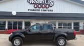 Black pickup truck parked in front of a Wheel City Auto Finance Centers building with large sign on the facade.