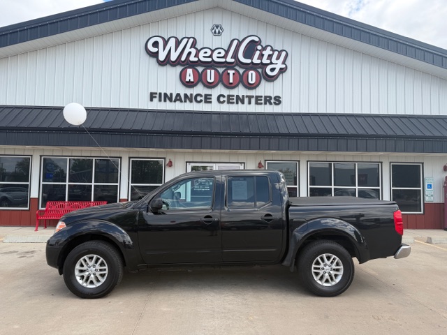 Black pickup truck parked in front of a Wheel City Auto Finance Centers building with large sign on the facade.