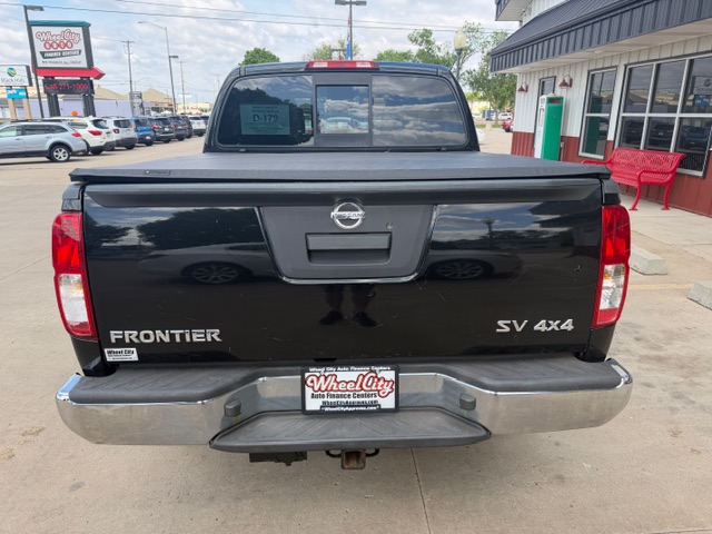 Rear view of a black Nissan Frontier SV 4x4 pickup on a dealership lot, with Wheel City license plate frame on the bumper.