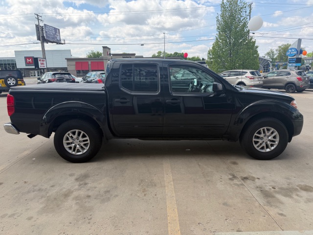 Black crew-cab pickup truck parked in a dealership lot, shown in a clear side profile with a long cargo bed and alloy wheels.