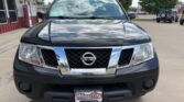 Front view of a black Nissan SUV with a chrome grille and Nissan emblem, parked in a dealership lot with a Wheel City plate frame.