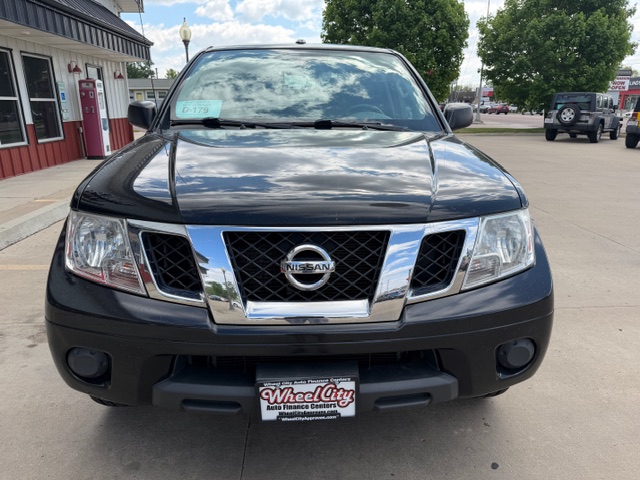 Front view of a black Nissan SUV with a chrome grille and Nissan emblem, parked in a dealership lot with a Wheel City plate frame.