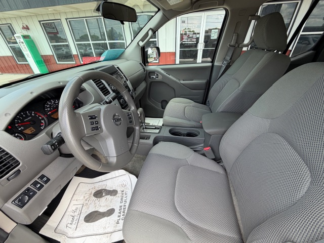 Interior of a gray pickup truck showing the steering wheel, dashboard gauges, center console, gear shifter, and front seats viewed from the driver’s side.