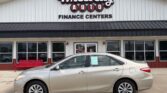 Beige four-door sedan parked in front of Wheel City Auto Finance Centers storefront with red bench nearby.