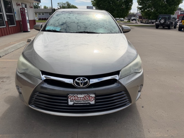 Front view of a silver Toyota sedan at a dealership, with Wheel City Auto license plate frame visible on the bumper.