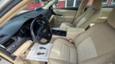 Interior of a beige sedan showing the driver and front passenger seats, dashboard, steering wheel, and center console with a floor mat on the driver’s side.