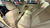 Beige fabric interior of a sedan, viewed from the rear side, showing the rear bench with three seat belts and front seats ahead.