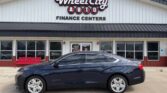 Blue sedan parked in front of Wheel City Auto Finance Centers storefront signage on a sunny day.