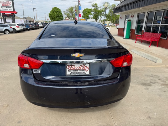 Black Chevrolet sedan parked in a dealership lot, rear view with Wheel City Auto Finance Centers plate frame and red tail lights.