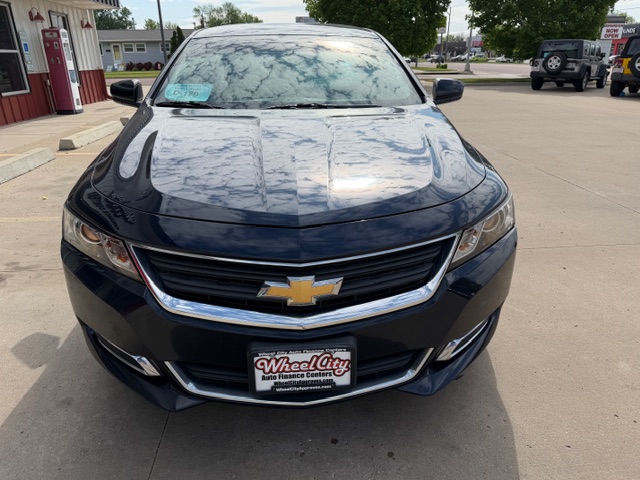 Front view of a black Chevrolet sedan in a parking lot, chrome grille with gold bowtie emblem and a dealership plate reading Wheel City Auto Finance Centers